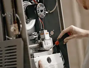 Furnace repair technician inspecting internal components and wiring in New Orleans, LA