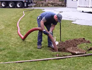 Septic pumping technician servicing a residential septic tank with a vacuum hose in New Orleans, LA