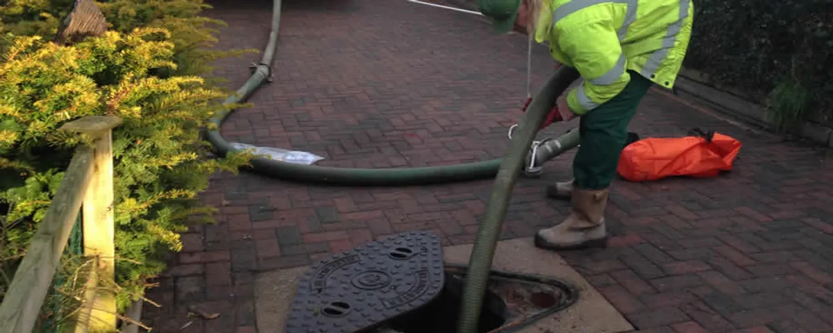 Septic tank cleaning technician servicing a septic tank with a vacuum hose in New Orleans, LA