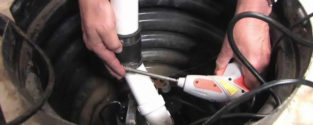 Sump pump installation technician connecting PVC discharge piping in New Orleans, LA