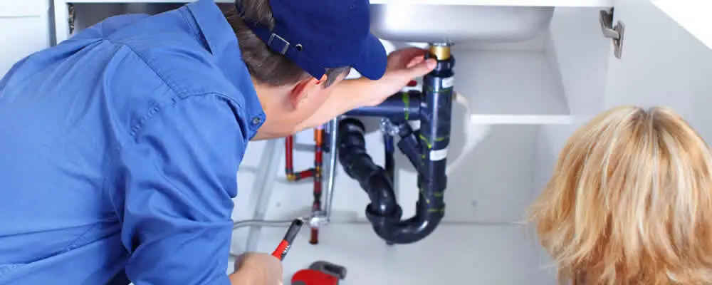 Plumber repairing under-sink drain pipes and fittings in New Orleans, LA