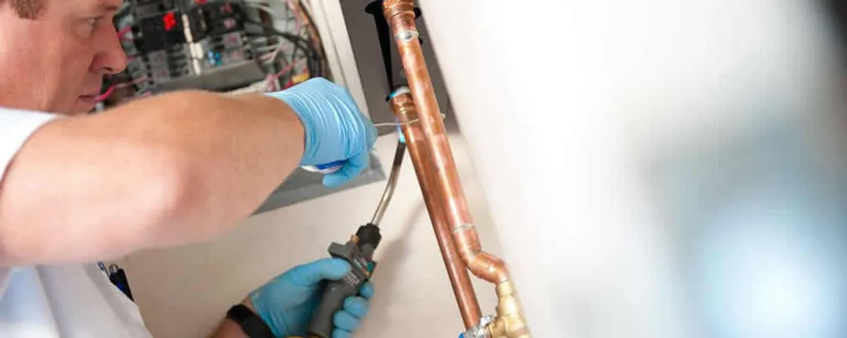 Water heater repair technician testing copper pipe connections and controls in New Orleans, LA